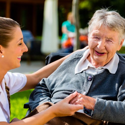 Nurse,Holding,Hands,With,Senior,Woman,Sitting,In,Wheelchair,In